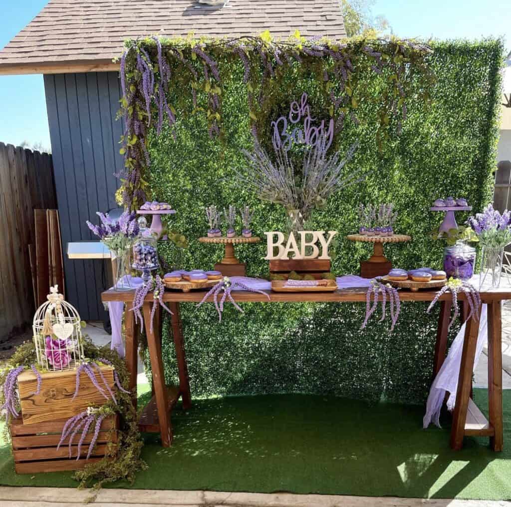Elegant baby shower dessert table with lavender and greenery decorations.