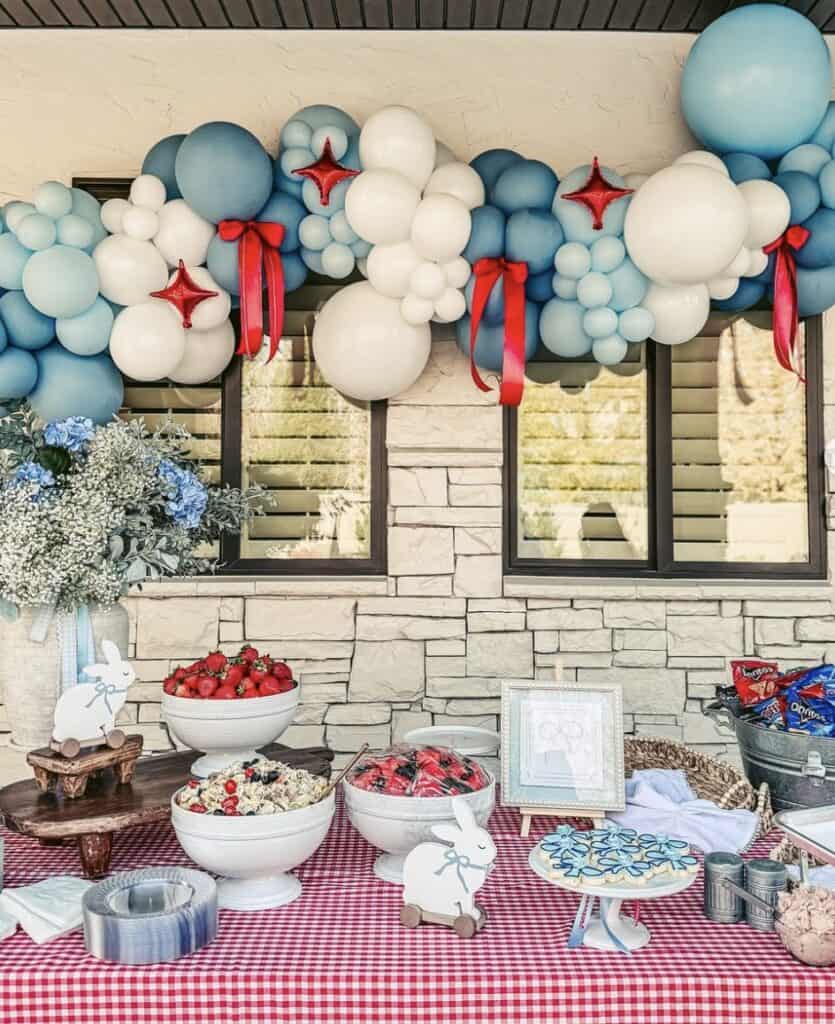 Balloon garland for party decor with red bows and star-shaped balloons, outdoor setting.