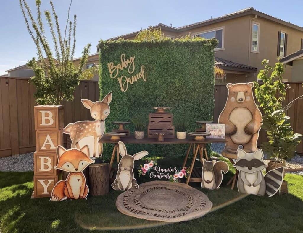 Woodland animal baby shower backdrop with forest theme and decorative cutouts.