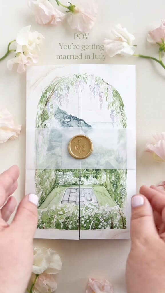 Elegant wedding invitation with watercolor garden scene and gold wax seal.