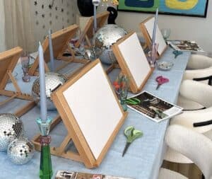 Colorful party planning table with blank canvases, candles, disco balls, and magazines.