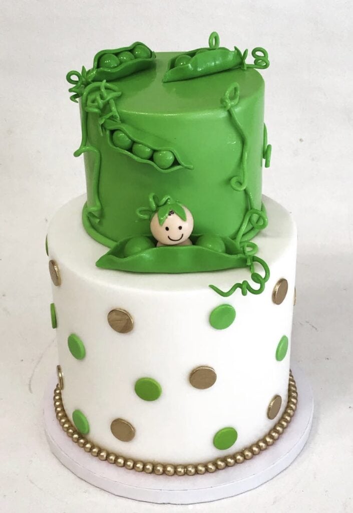Vegan cake with green edible plants and a smiling ladybug topper for nature-themed birthday celebration.