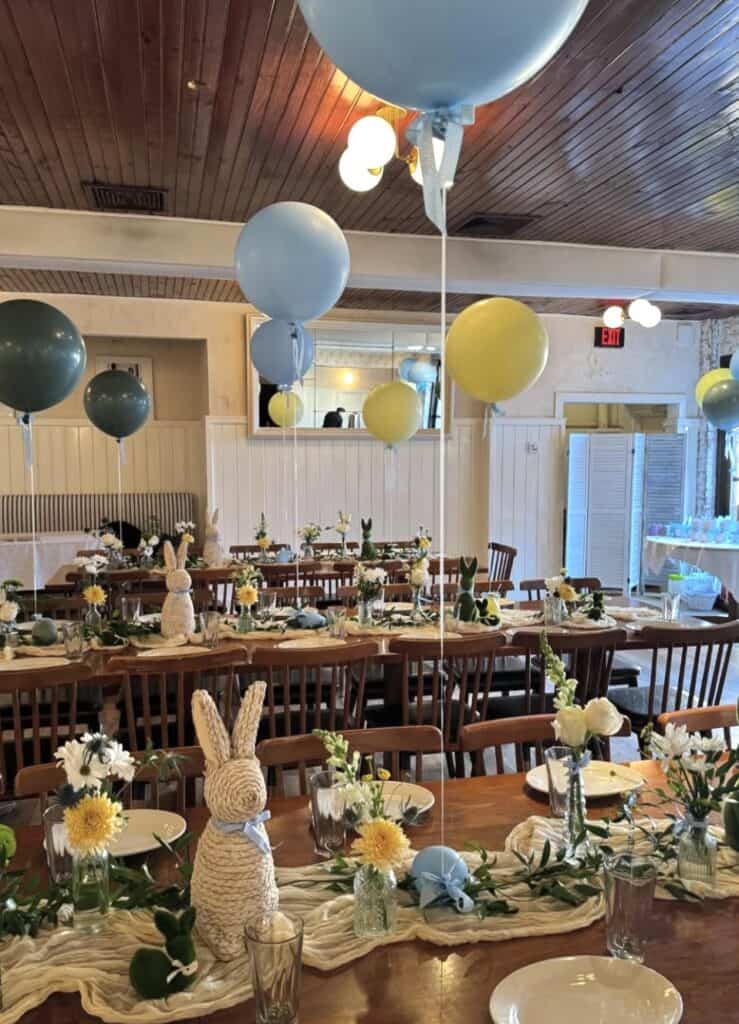 Colorful Easter celebration decor with balloons, bunny figurines, and floral arrangements.