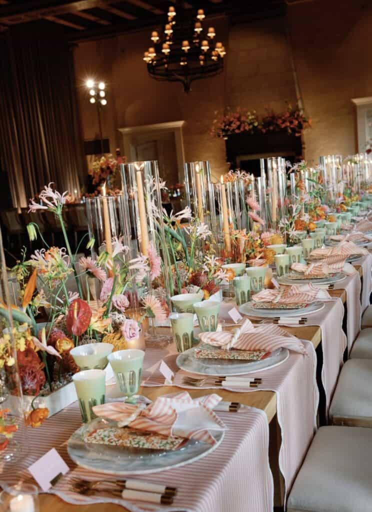 Elegant wedding table setting with floral centerpieces and pink striped napkins.