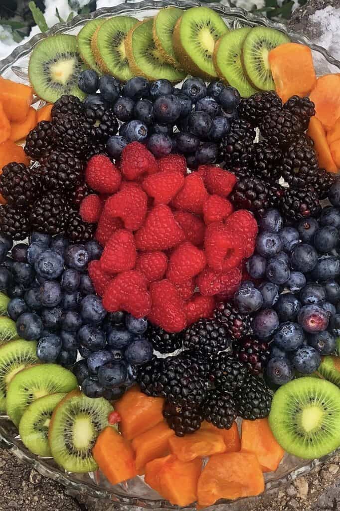 Fresh mixed berries and tropical fruit platter with blueberries, raspberries, blackberries, kiwi, and papaya.