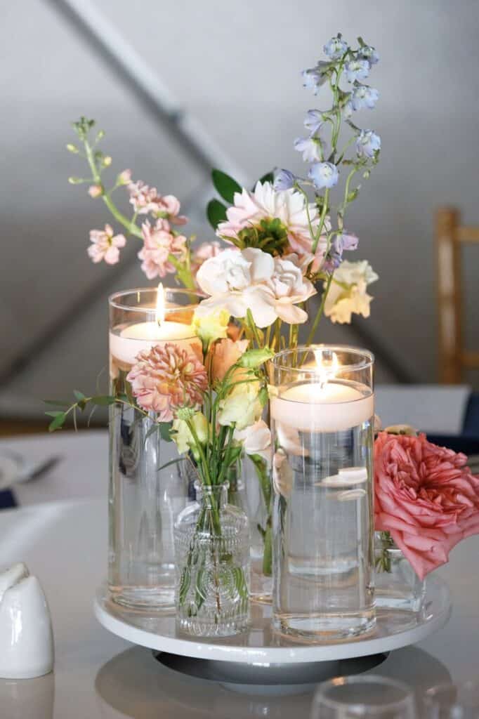 Elegant floral centerpiece with candles, roses, and hydrangeas for wedding decor.