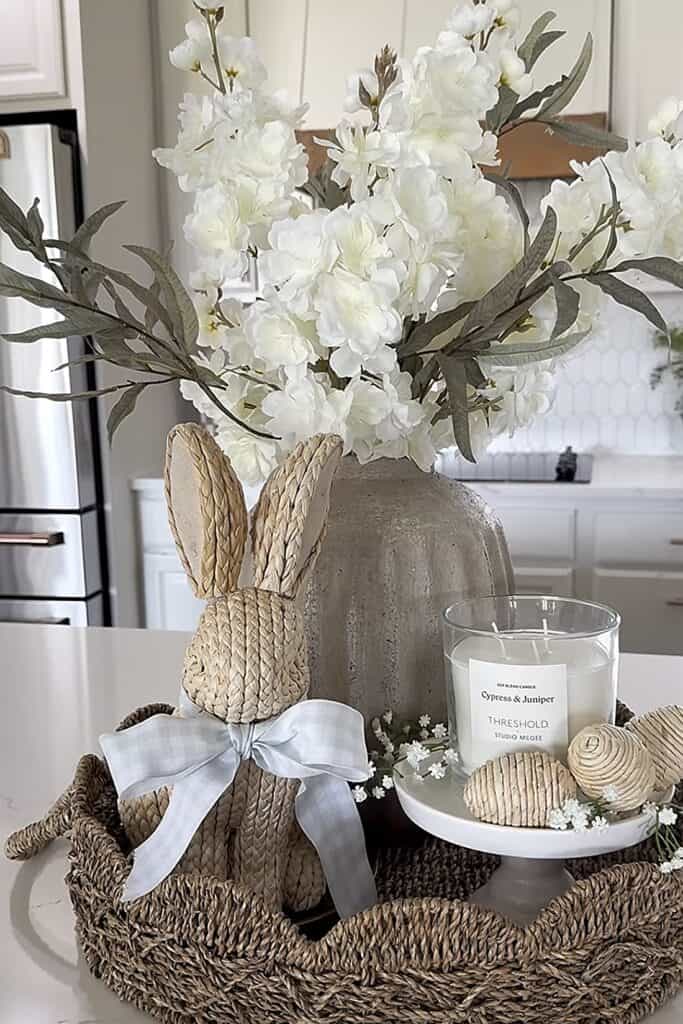 Elegant white floral arrangement with decorative Easter bunny and candles for spring decor.