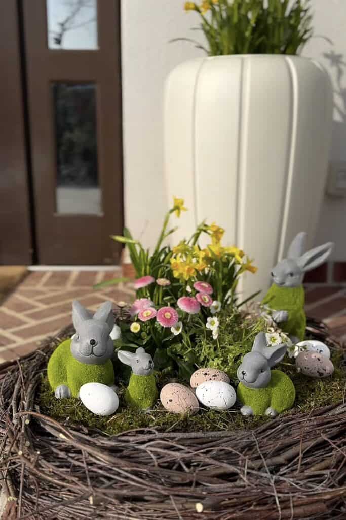 Colorful Easter bunny and egg decorations with spring flowers in a nest, outdoor decor.