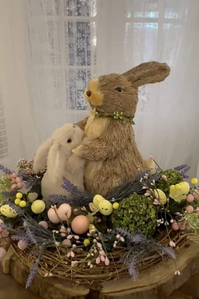 Whimsical Easter bunny decor with plush rabbits and floral centerpiece on wooden table.