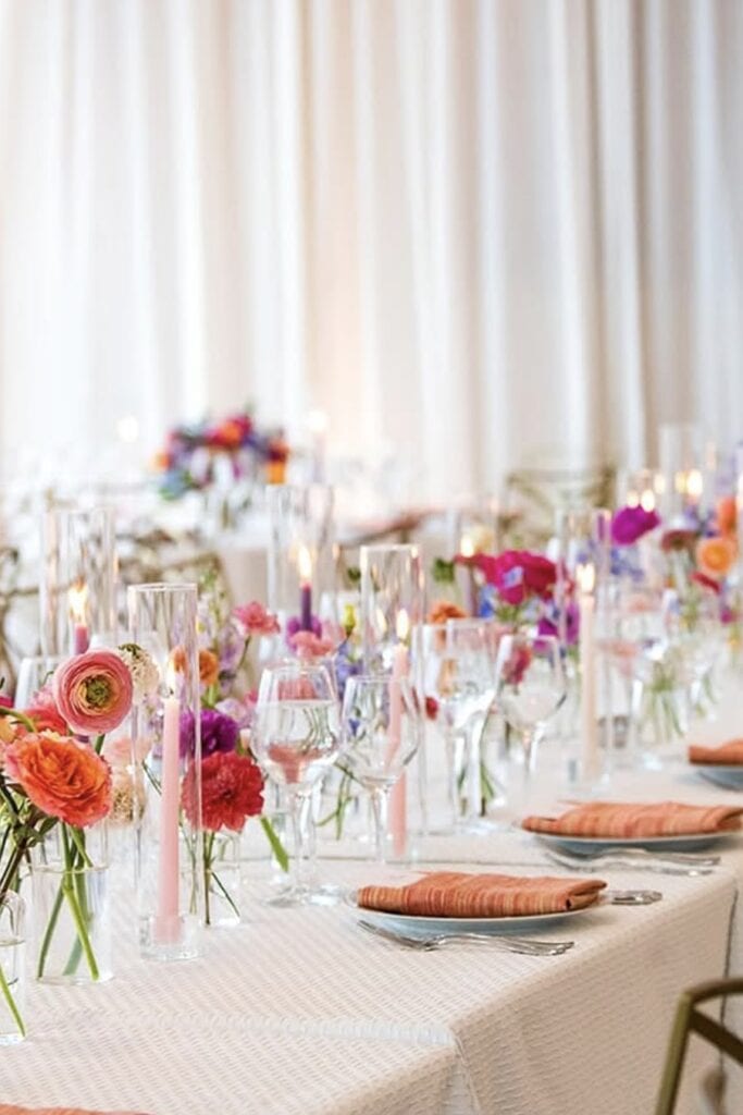 Elegant floral wedding table decor with colorful blooms and candles.