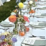 Colorful floral wedding table centerpiece with fresh flowers and elegant place settings.