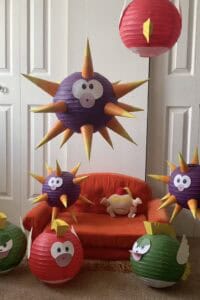 A colorful DIY Mario-themed birthday party decoration with spiky purple and red paper lanterns resem.