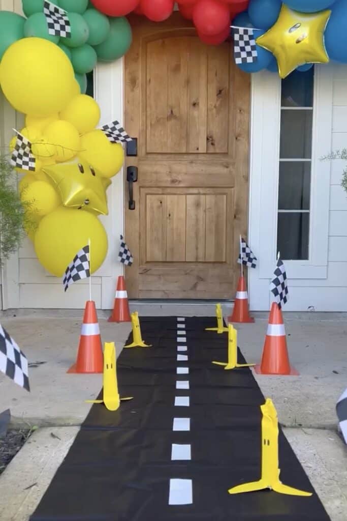 Mario Kart themed birthday party entrance with race track, balloons, and checkered flags.