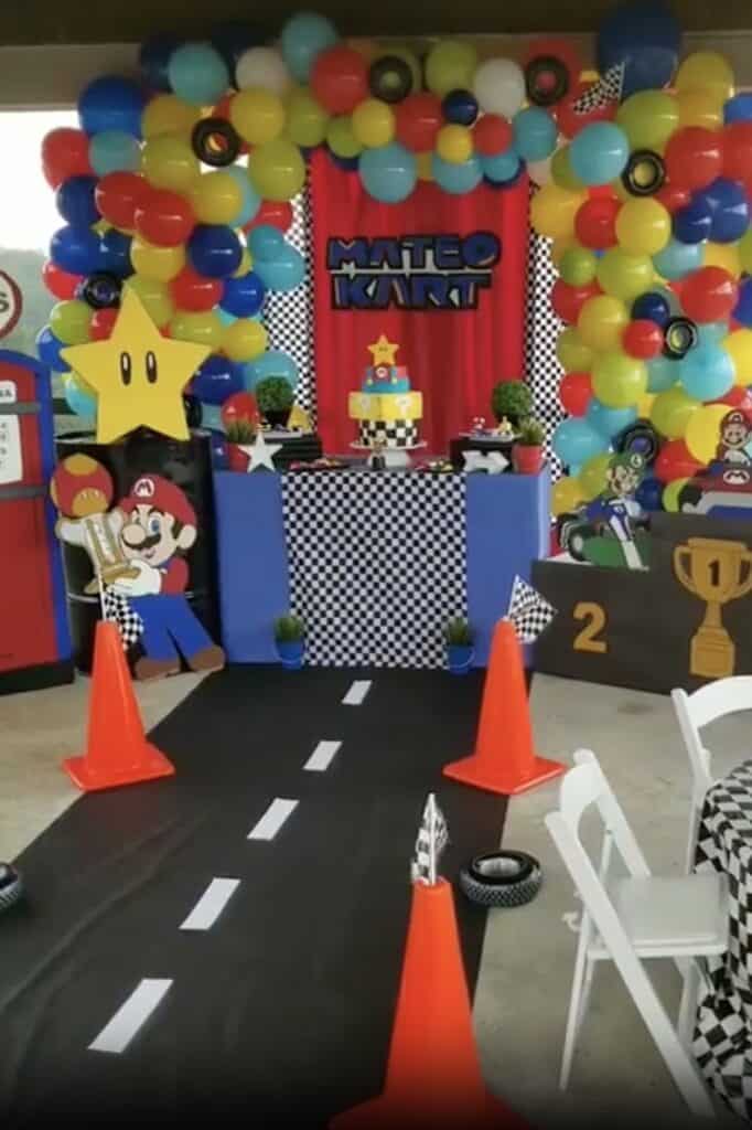 Mario Kart themed birthday party setup with colorful balloons, race track, and Mario decorations.