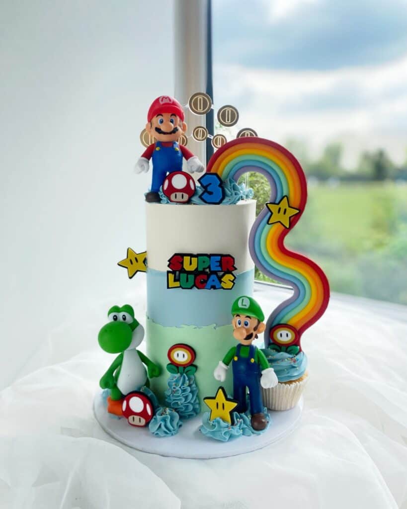 Super Mario-themed birthday cake with Mario, Luigi, Yoshi, and rainbow decorations.