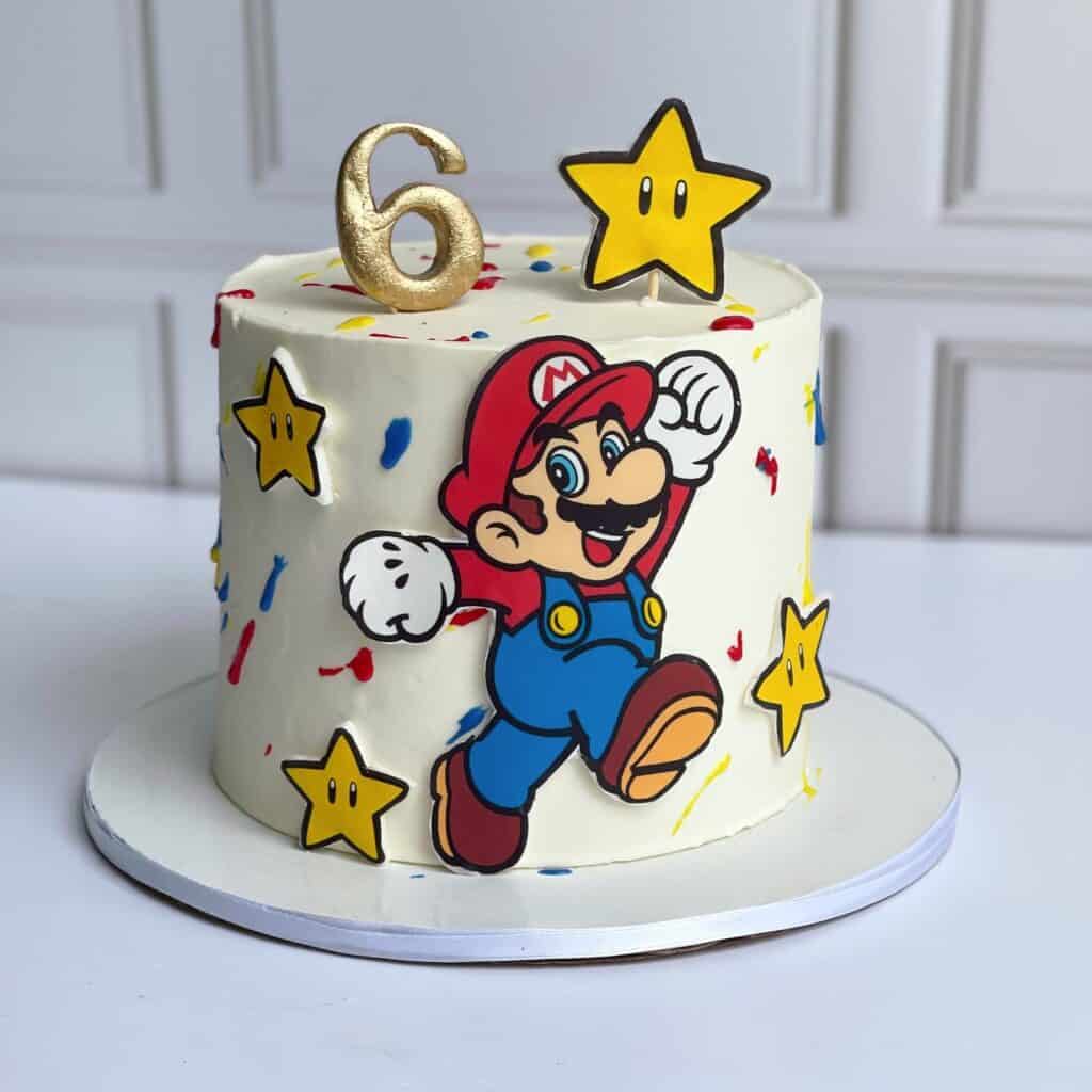 Mario-themed birthday cake with Super Mario character, stars, and number 6 topper, for kids' celebra.