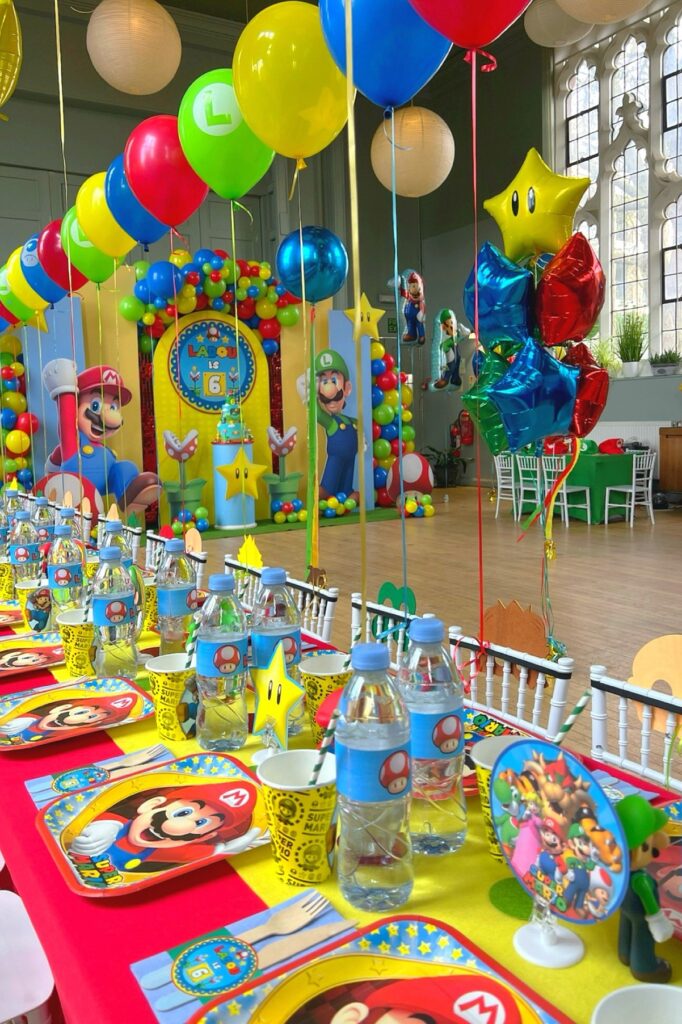 A colorful Super Mario-themed birthday party setup with balloons, decorations, and themed tableware.