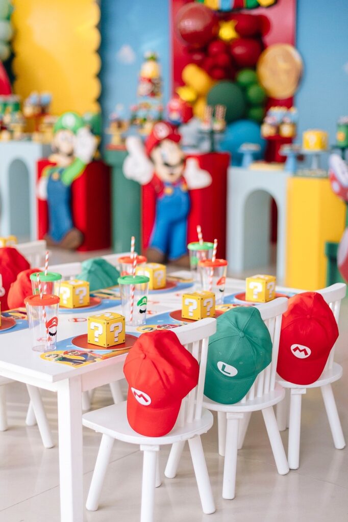 Mario-themed birthday party setup with colorful decorations, hats, and themed tableware.