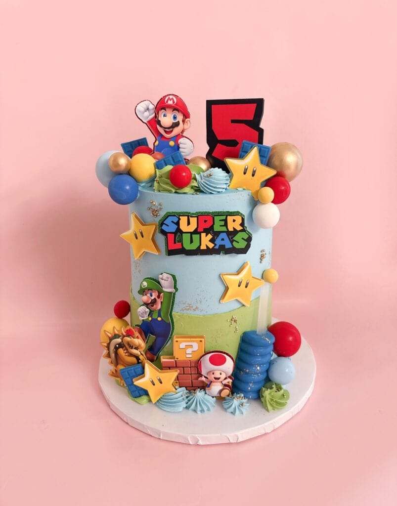 Super Mario-themed birthday cake with colorful decorations and character toppers for a child's celeb.