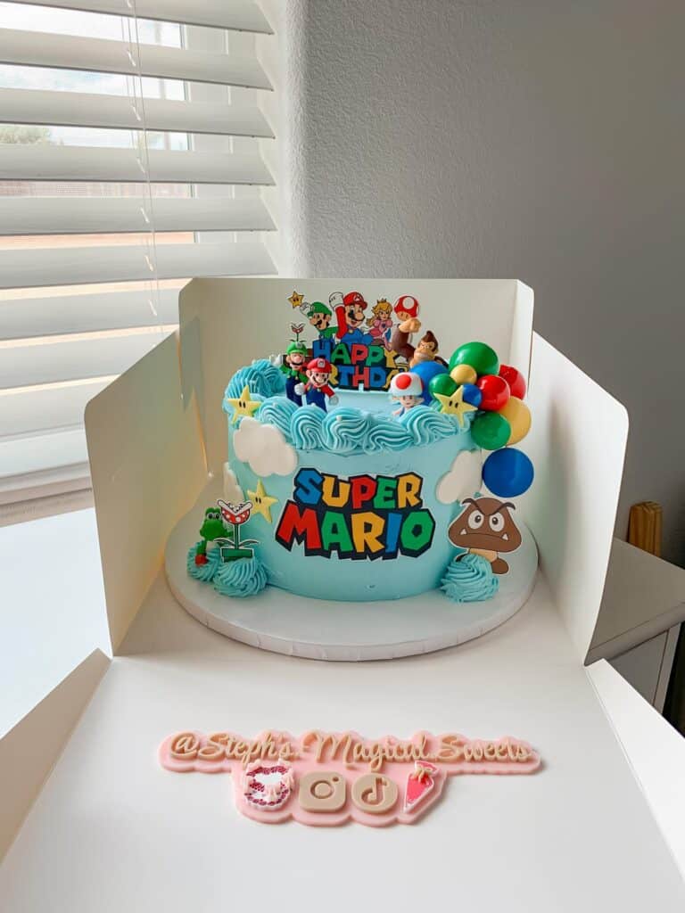 A colorful Super Mario-themed birthday cake with Mario, Luigi, and Princess Peach figurines, decorat.