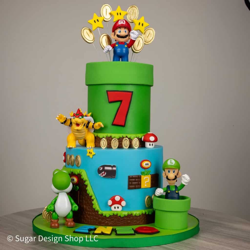 Super Mario-themed birthday cake with Mario, Luigi, Yoshi, and Bowser figurines, colorful decoration.