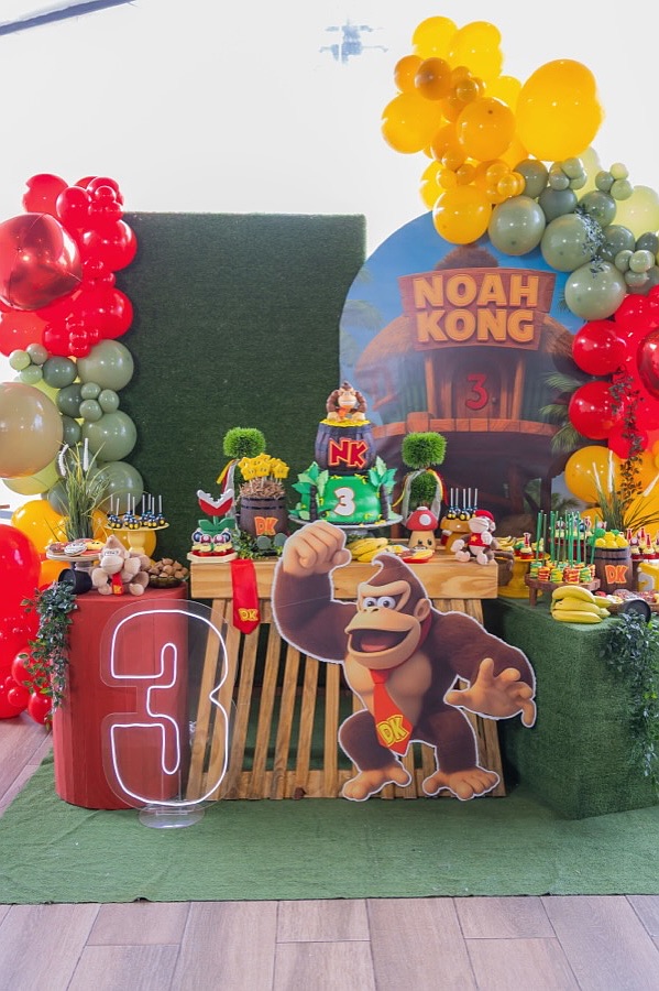 A colorful Donkey Kong themed birthday party setup with balloons, decorations, and a cake.