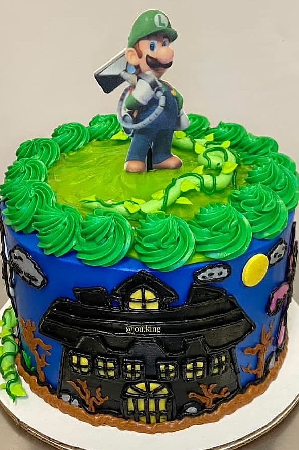 Luigi cake with green frosting and mansion design for birthday party celebration.