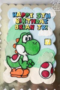 A colorful Yoshi-themed birthday cake with "Happy 5th Birthday Brian Jr." message, perfect for a Mar.