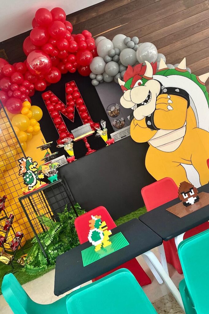A colorful Bowser-themed birthday party setup with balloons, decorations, and themed tableware.