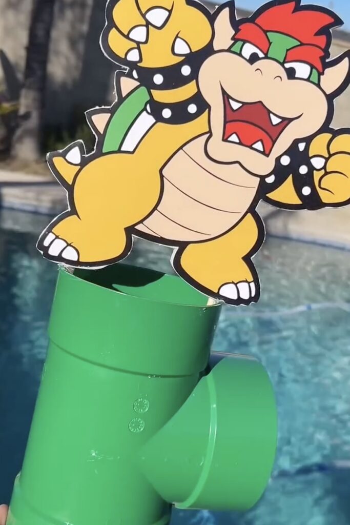 A colorful Bowser-themed birthday decoration with a water slide at a party.