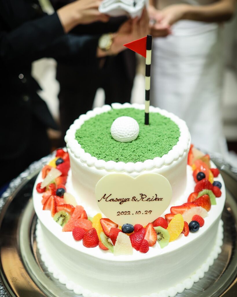 A lush wedding cake decorated with fresh fruit and a golf-themed topper, celebrating love.