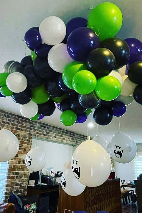 A colorful balloon arrangement with black, white, green, and purple balloons, featuring ghost faces.