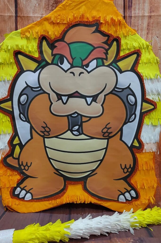 A colorful Bowser-themed birthday party piñata with vibrant yellow, orange, and white fringes.