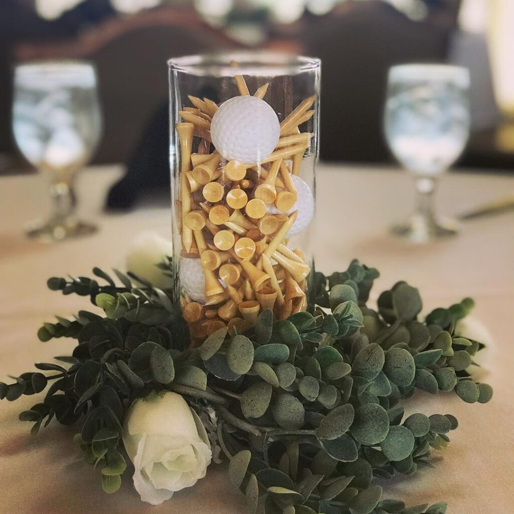 Confetti and roses centerpiece with golf ball-shaped confetti and greenery for wedding decor.