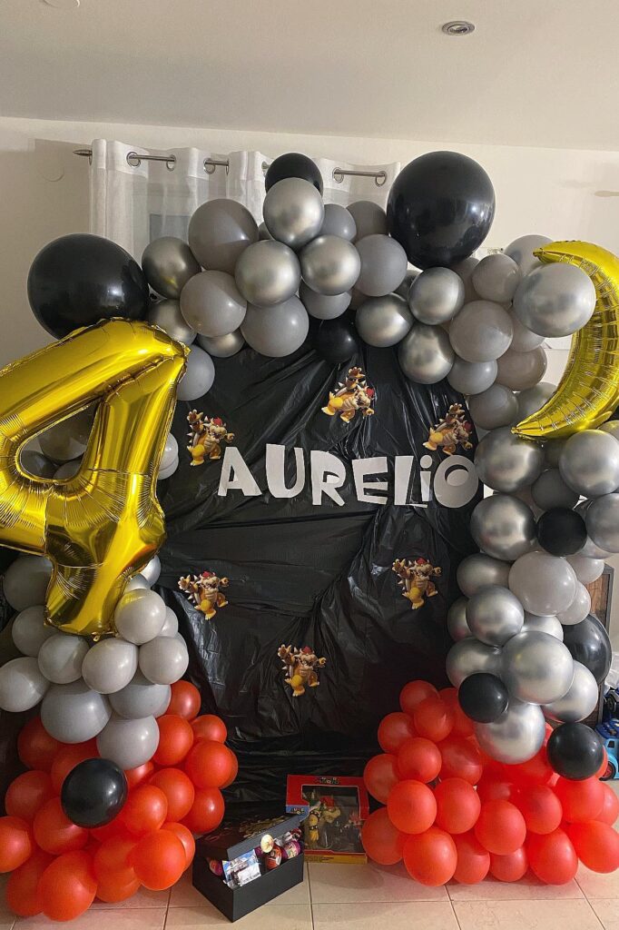 A colorful balloon arch with black, silver, red, and gold balloons for a birthday celebration.
