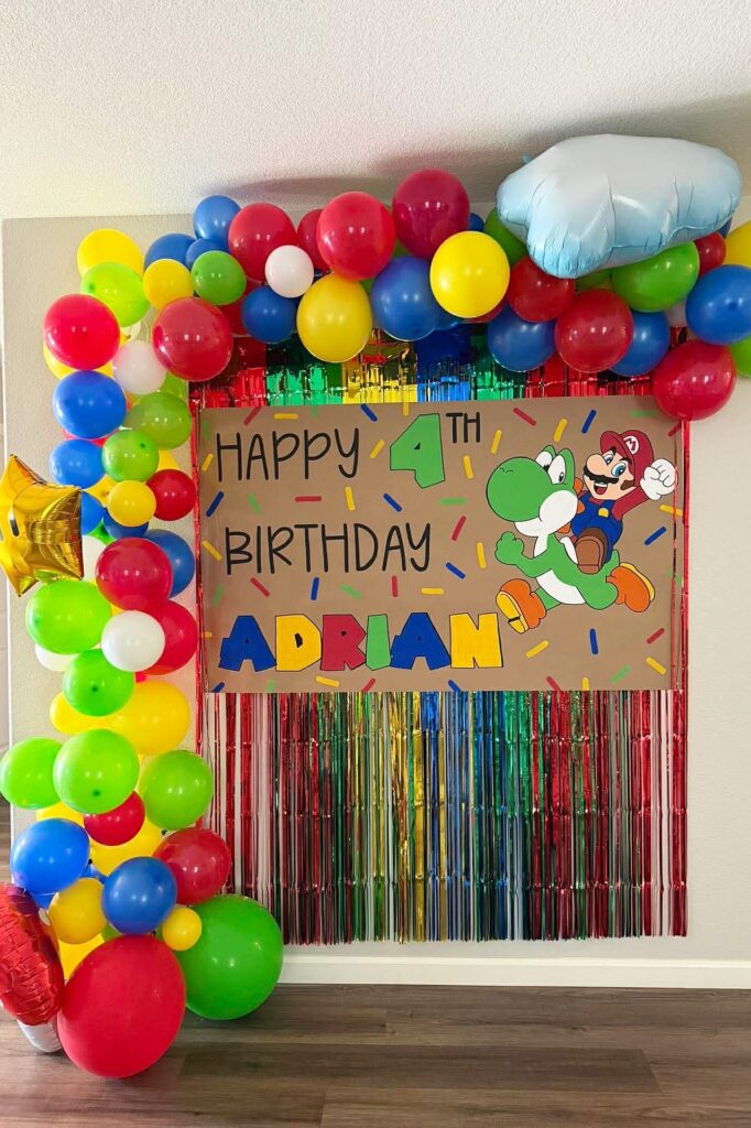 A colorful balloon decoration with a Yoshi-themed birthday sign for a 4th birthday celebration.