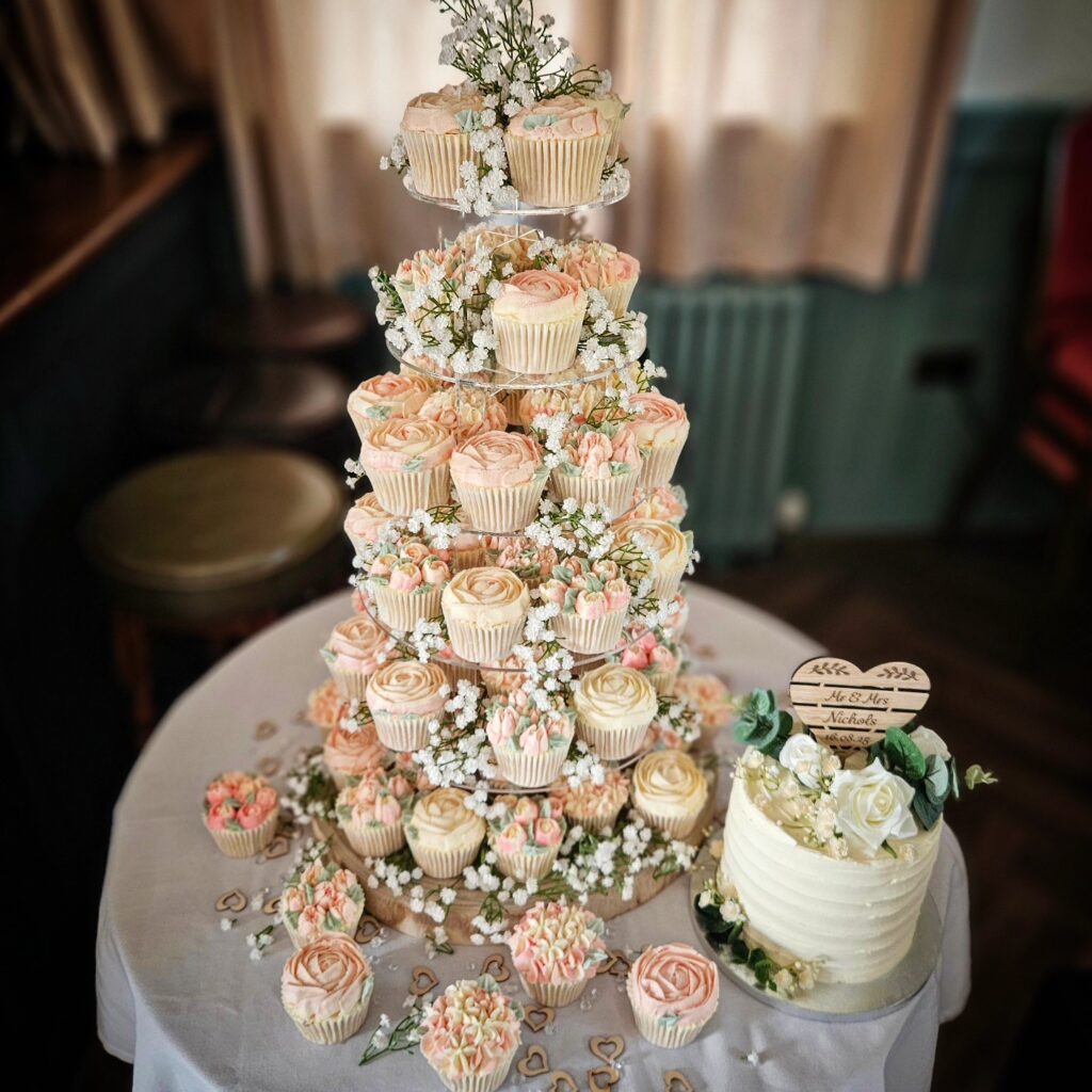 Elegant cupcake tower with floral decorations for wedding celebration.