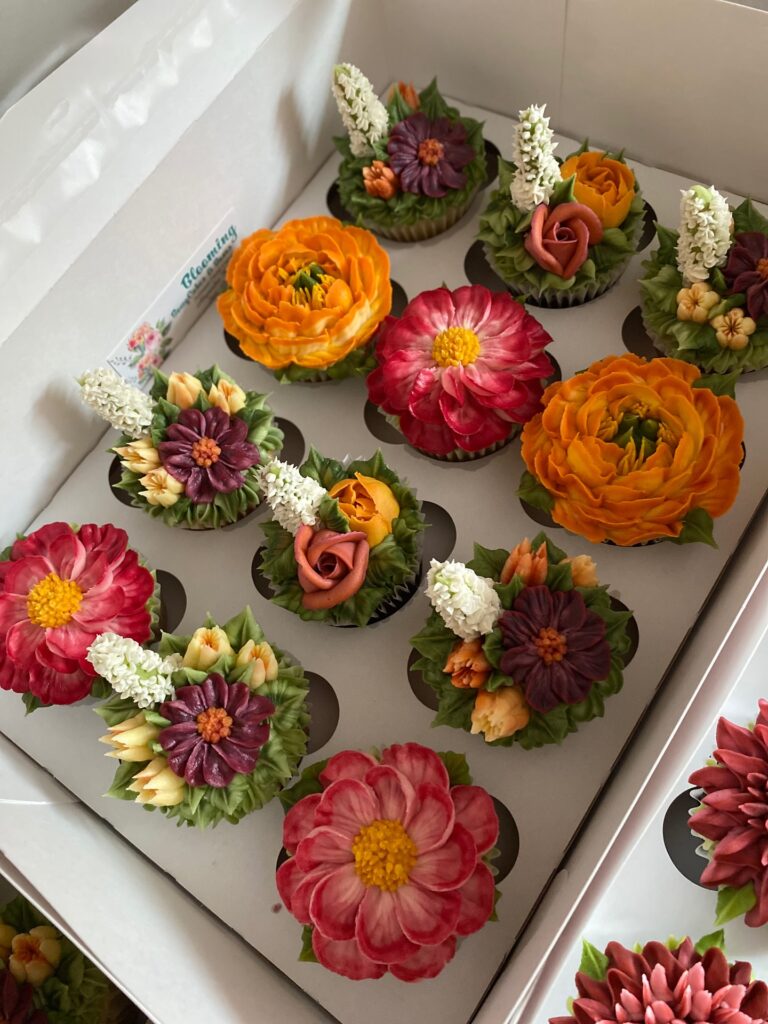 Colorful floral wedding cupcakes with vibrant buttercream flowers in a box.