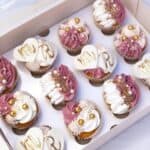 Elegant wedding cupcakes with gold and pearl decorations in a box for a wedding celebration.