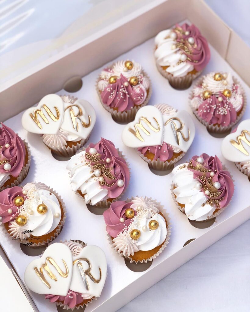 Elegant wedding cupcakes with gold and pearl decorations in a box for a wedding celebration.
