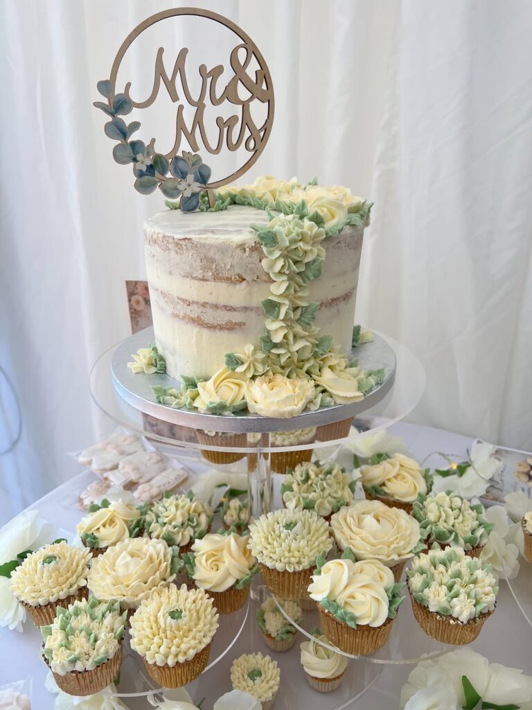 Wedding cake with floral decorations and cupcakes for a wedding celebration.