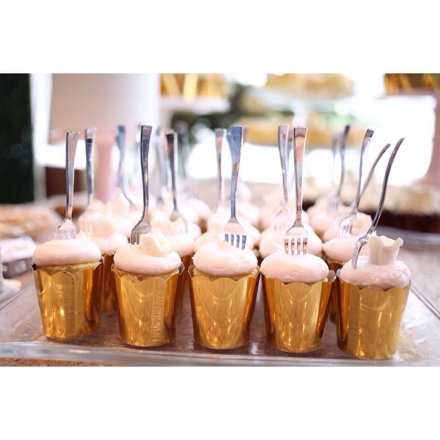 Elegant champagne cupcakes with pink frosting and silver forks for wedding celebration.