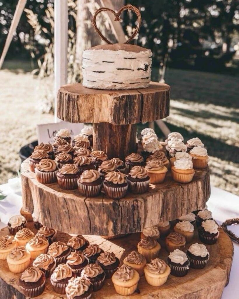Rustic wedding cupcake display with a wooden tiered stand and a small cake topper.