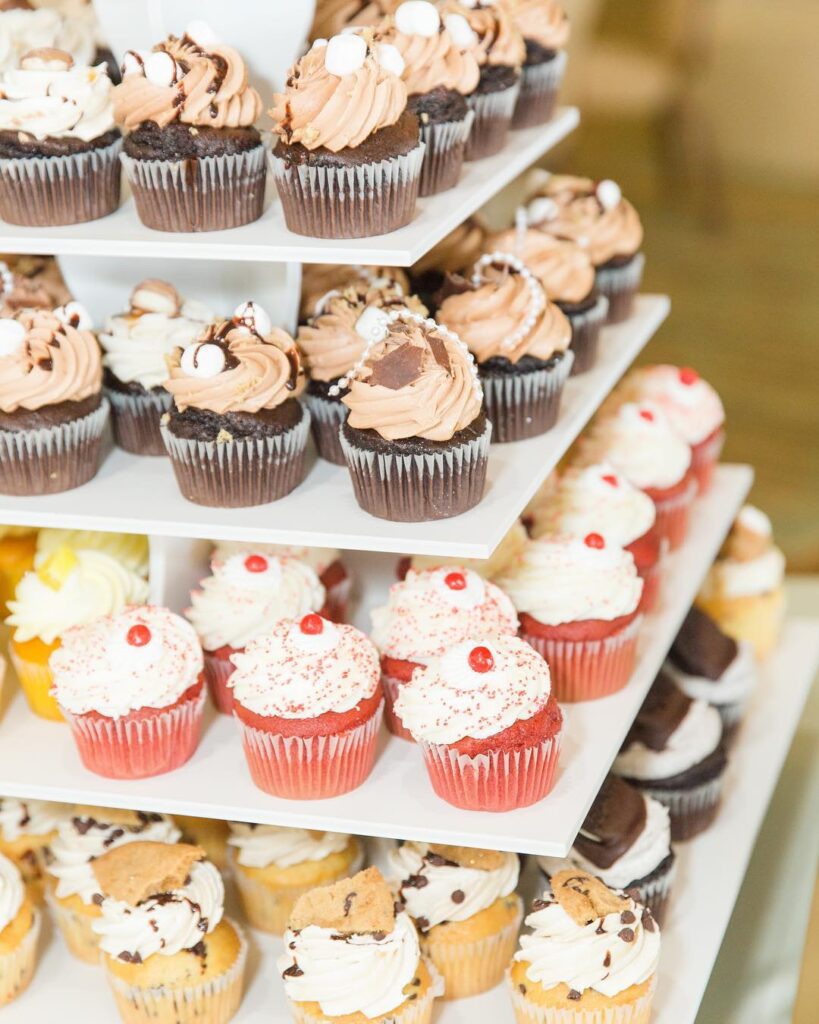 Assorted wedding cupcakes with various frosting designs on a tiered stand.
