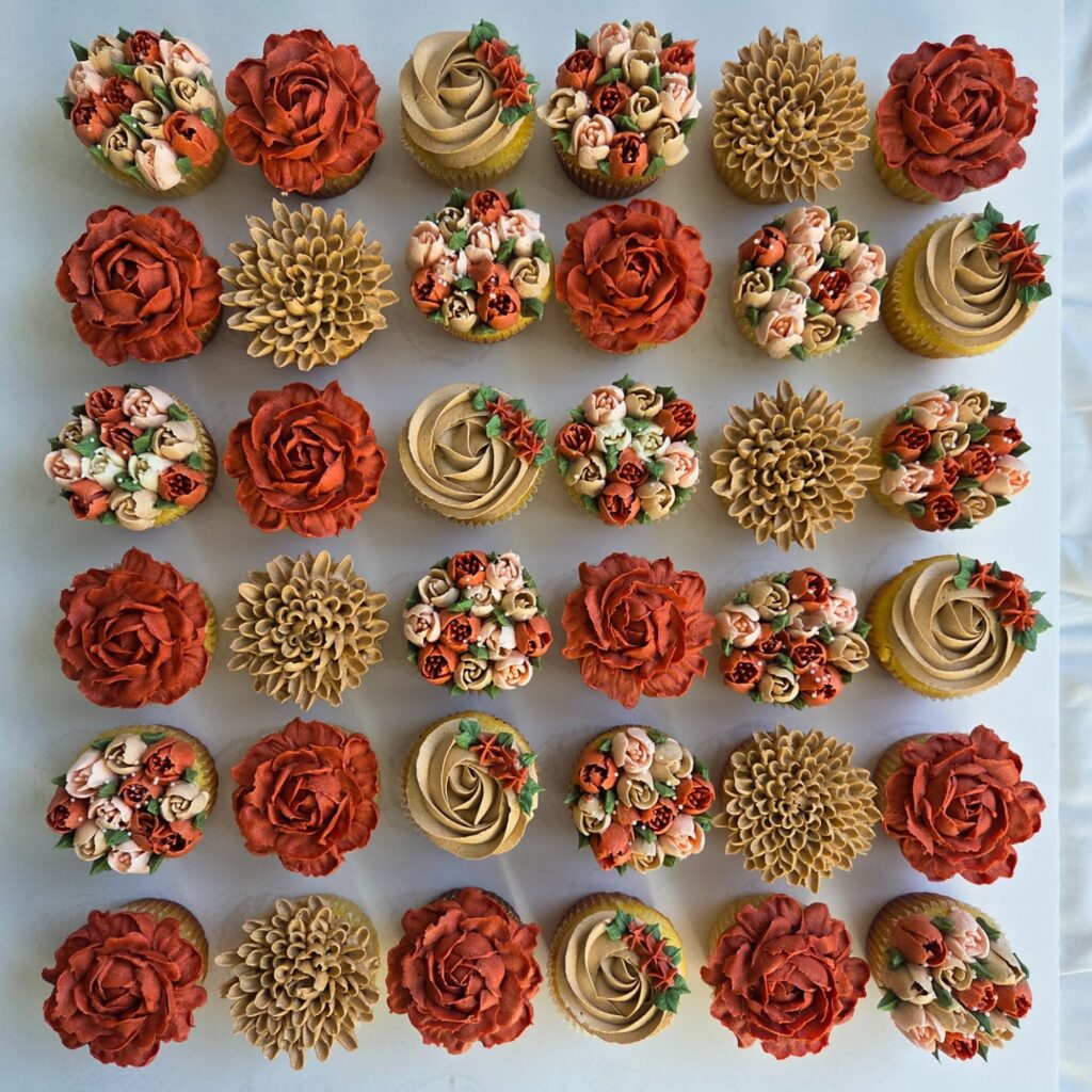 Assorted wedding cupcakes with floral and rosette designs for wedding celebration.