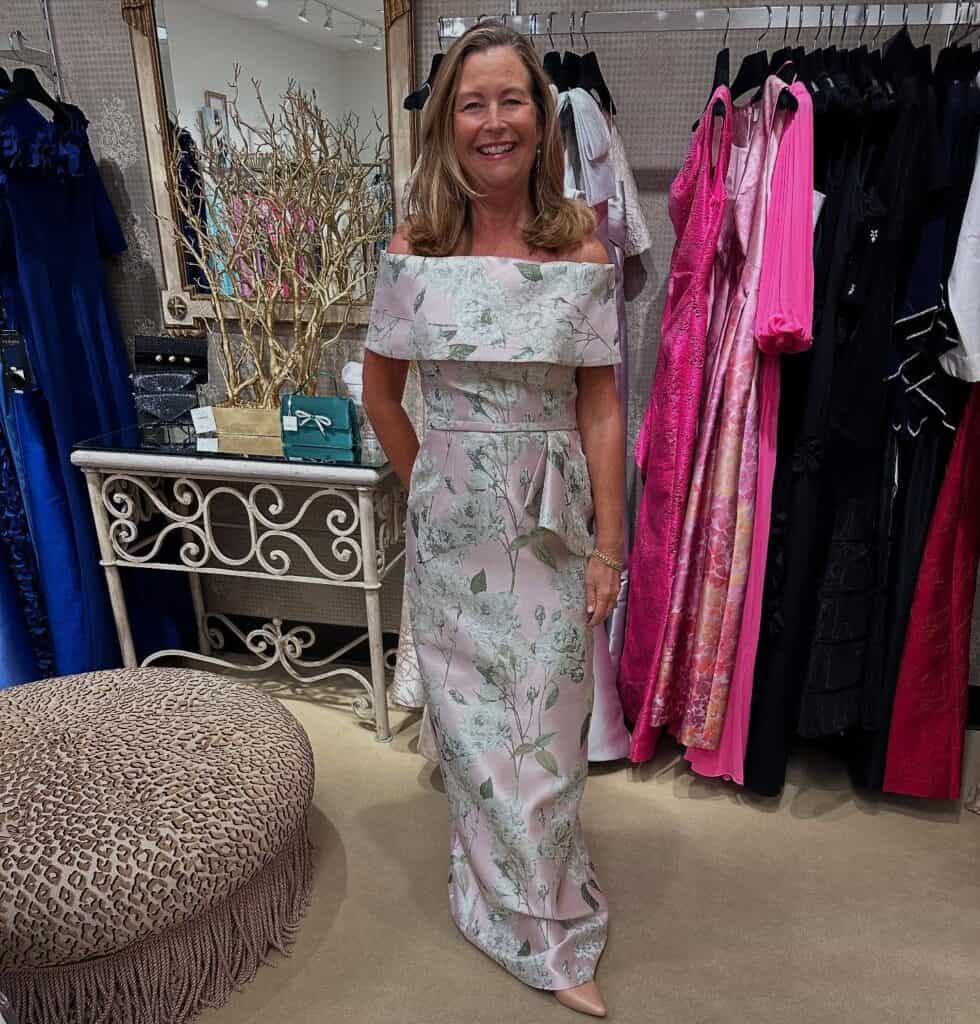 Elegant woman in floral off-shoulder dress shopping at Confetti & Roses boutique.