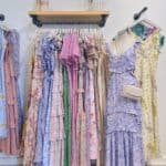 Floral maxi dresses and sundresses displayed on a clothing rack at Confetti & Roses boutique.