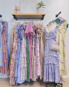 Floral maxi dresses and sundresses displayed on a clothing rack at Confetti & Roses boutique.