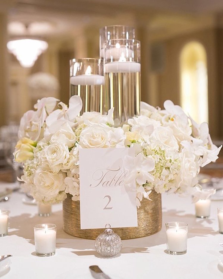 Elegant wedding centerpiece with floating candles and white roses for reception decor.