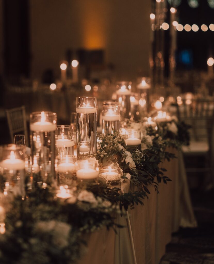 Elegant wedding reception table with floating candles and floral centerpieces at night.